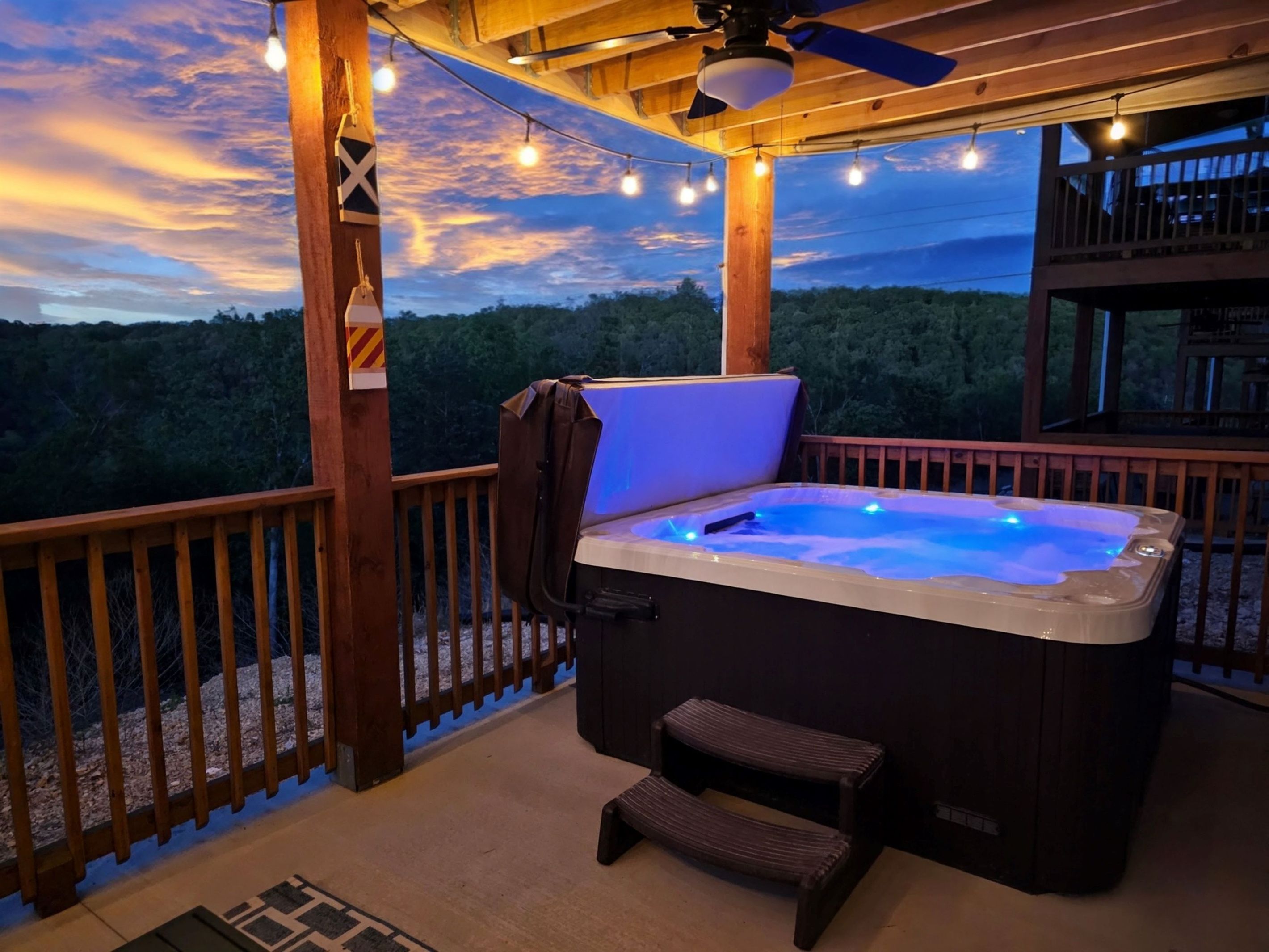 Un jacuzzi en una terraza de madera con vistas al bosque.