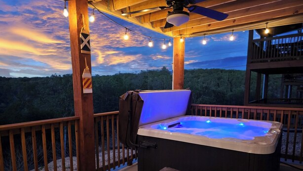A hot tub on a wooden deck with a view of a forested area. - Modern Family Lodge 1 Mi to Silver Dollar City, Indoor Pool, Hot Tub, Arcade, EV (Branson)