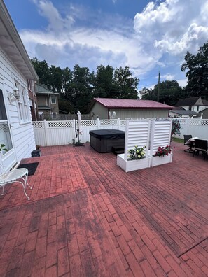 A patio with red brick flooring, white lattice fence, and outdoor furniture.