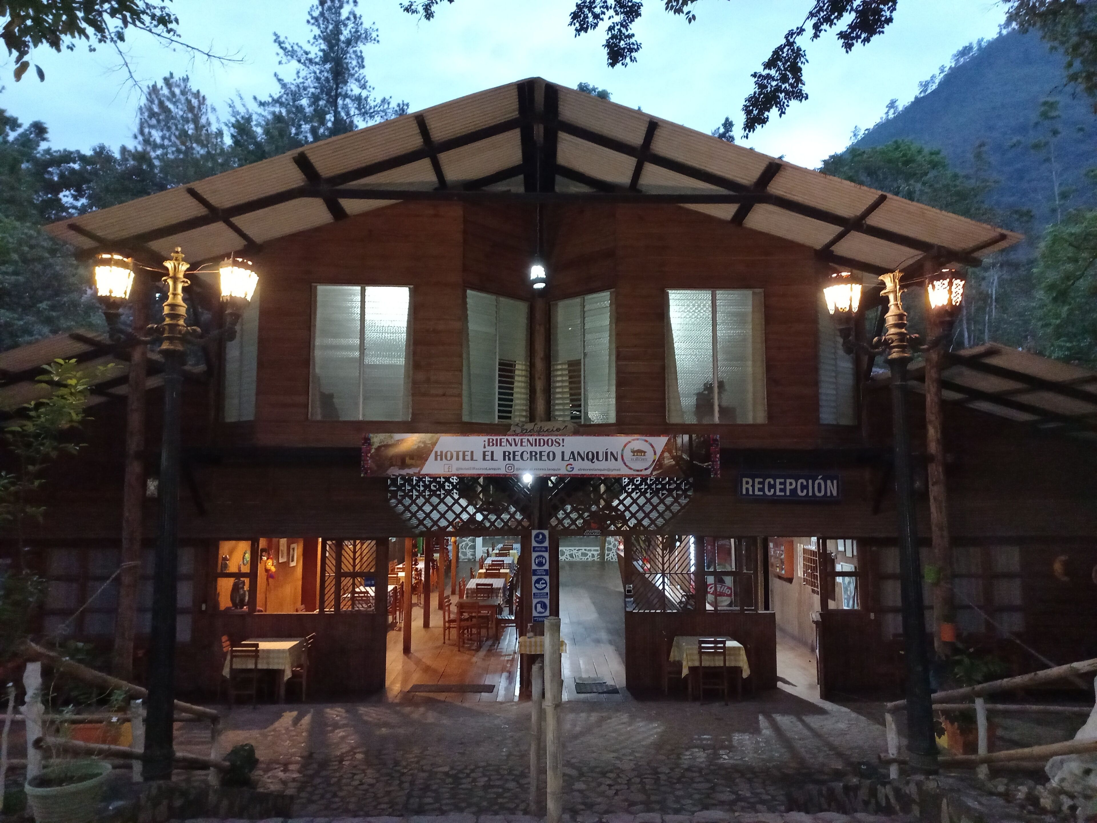 A two-story hotel with a reception area, wooden exterior, and outdoor seating.