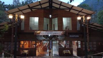 A two-story hotel with a reception area, wooden exterior, and outdoor seating.