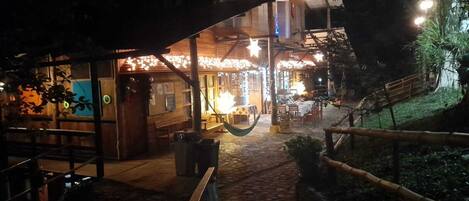 Un espacio de comedor al aire libre de estilo rústico, con una estructura de madera, un camino de piedra y una hamaca.