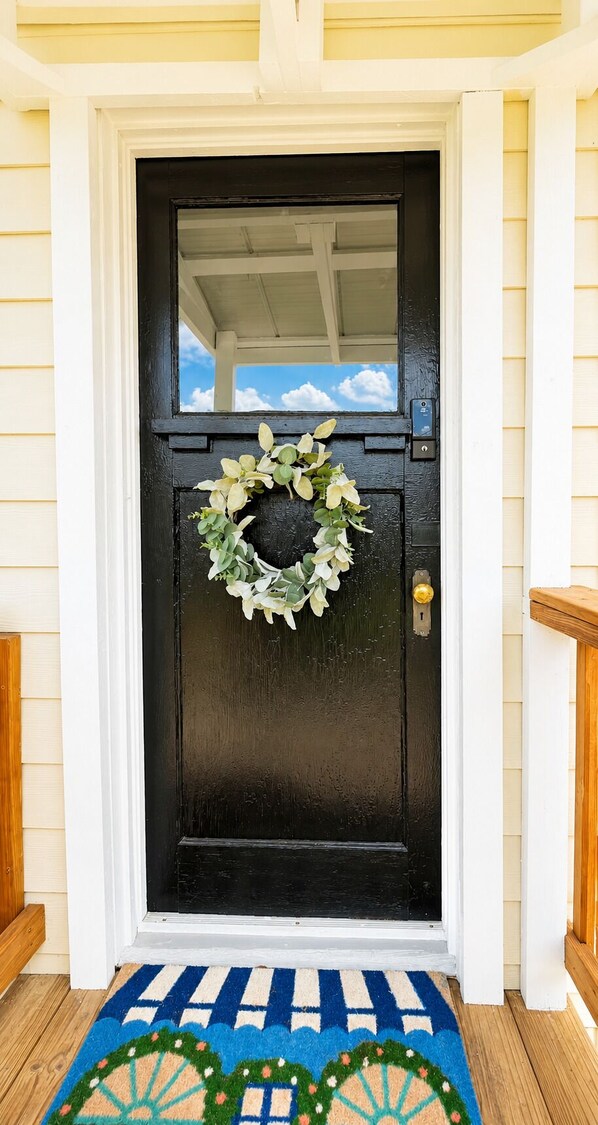 A black door with a wreath, a keyhole, and a small mailbox.