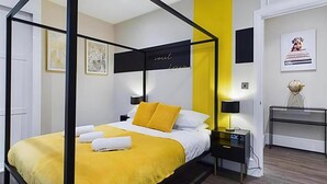 Una habitación de hotel moderna con cama con dosel, una pared de acento amarilla y un diseño minimalista.