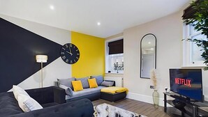 Una sala de estar moderna con un sofá, una mesa de centro, un televisor y un reloj de pared.