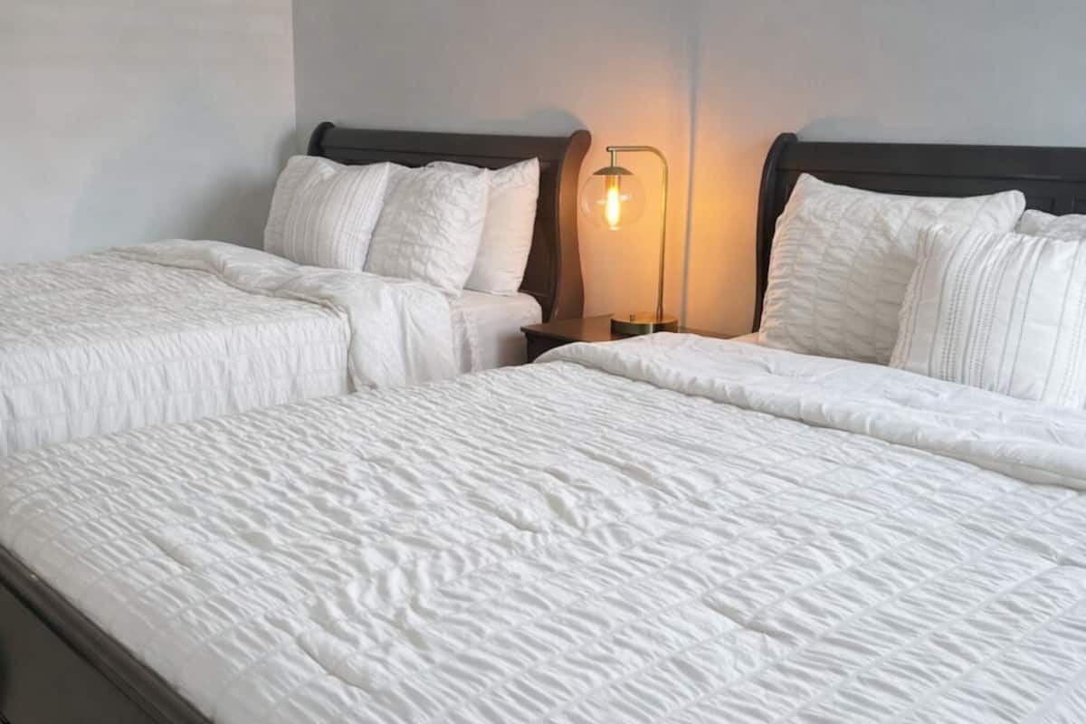 Un lit double avec une literie blanche et une table de chevet avec une lampe.