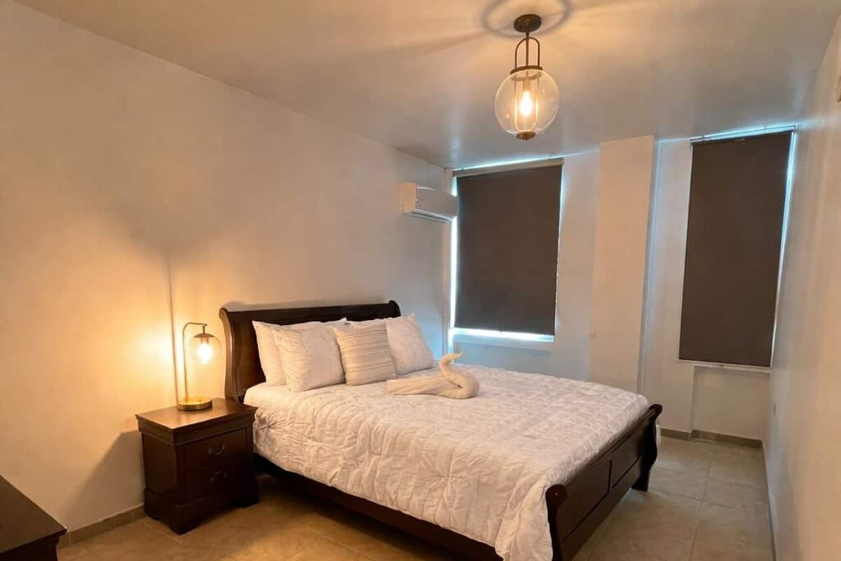 Une chambre à coucher avec un lit, une table de chevet et un coussin en forme de cygne.