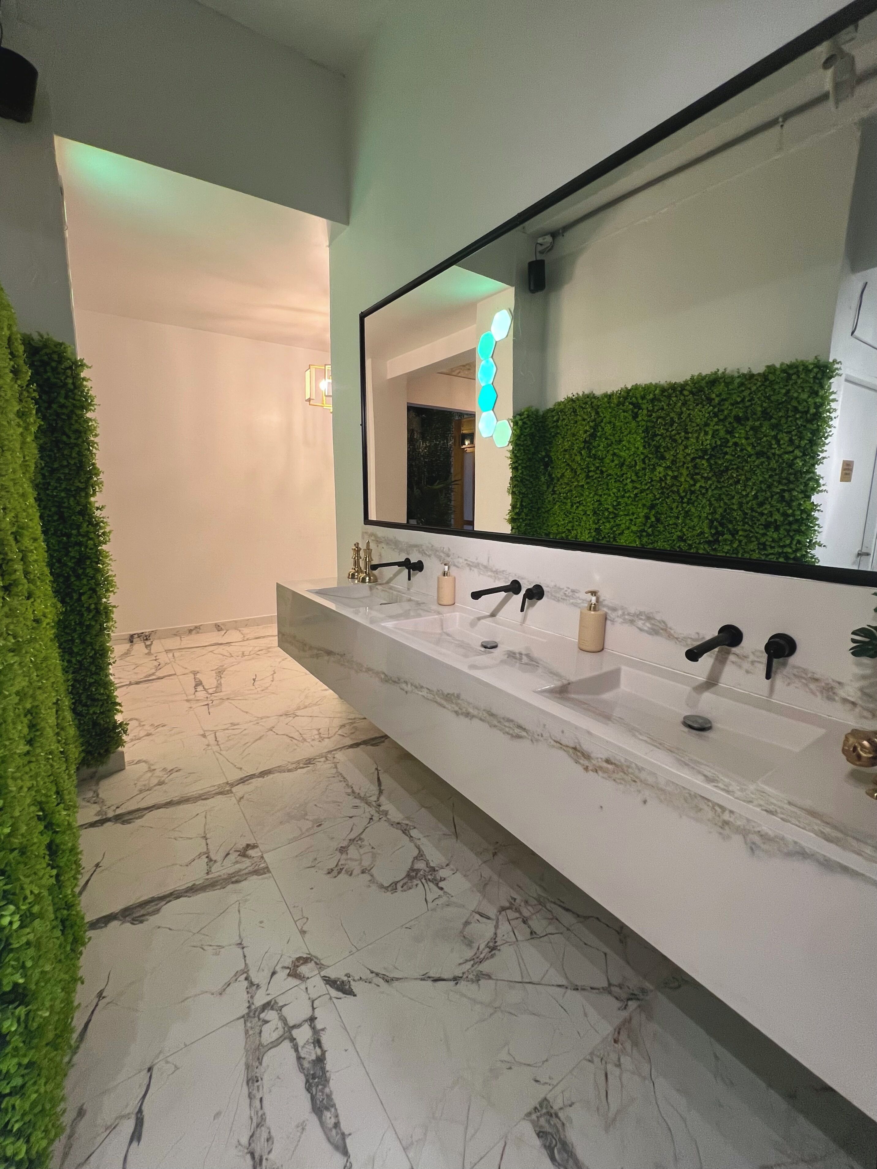 Une salle de bain moderne avec un lavabo en marbre, un grand miroir et des éléments décoratifs de verdure.