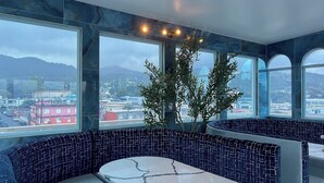 Un intérieur moderne avec un coin salon, de grandes fenêtres et une vue sur le paysage urbain.