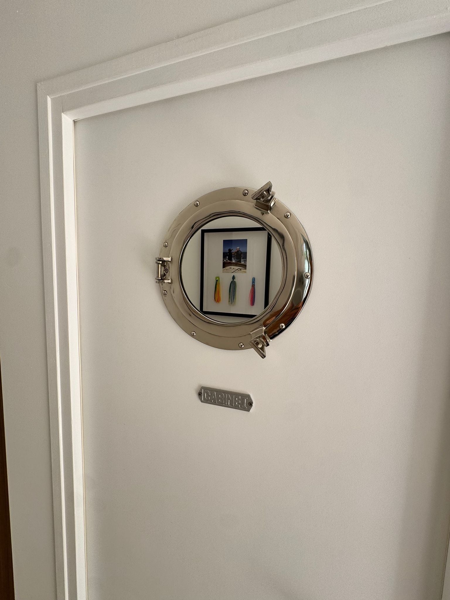 Una puerta con un espejo circular y una pequeña placa que dice "CABINET".