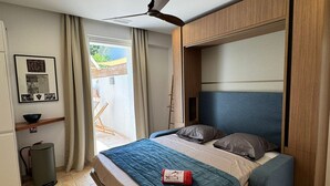 Une chambre à coucher moderne avec un lit, un ventilateur de plafond, un petit bureau et une fenêtre avec des rideaux.