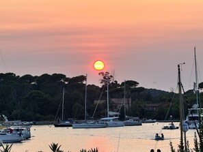 A marina with boats docked, surrounded by trees and buildings. - Hotel Les Jardins de Porquerolles (Hyères)