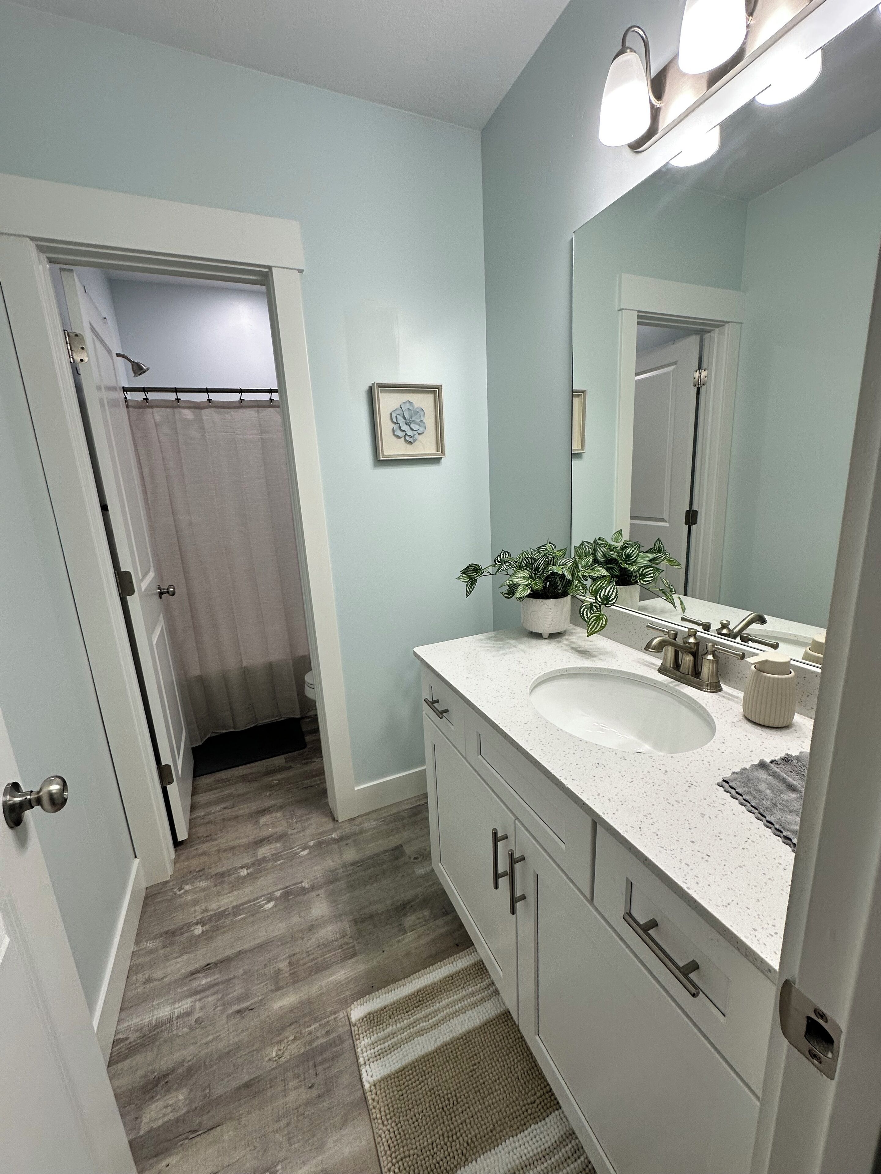 A bathroom with a white sink, mirror, and a shower curtain.