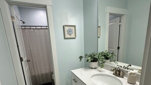Een badkamer met een witte wastafel, spiegel en douchegordijn.