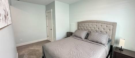 Un dormitorio con una cama grande, una mesita de noche, un aparador y una puerta.