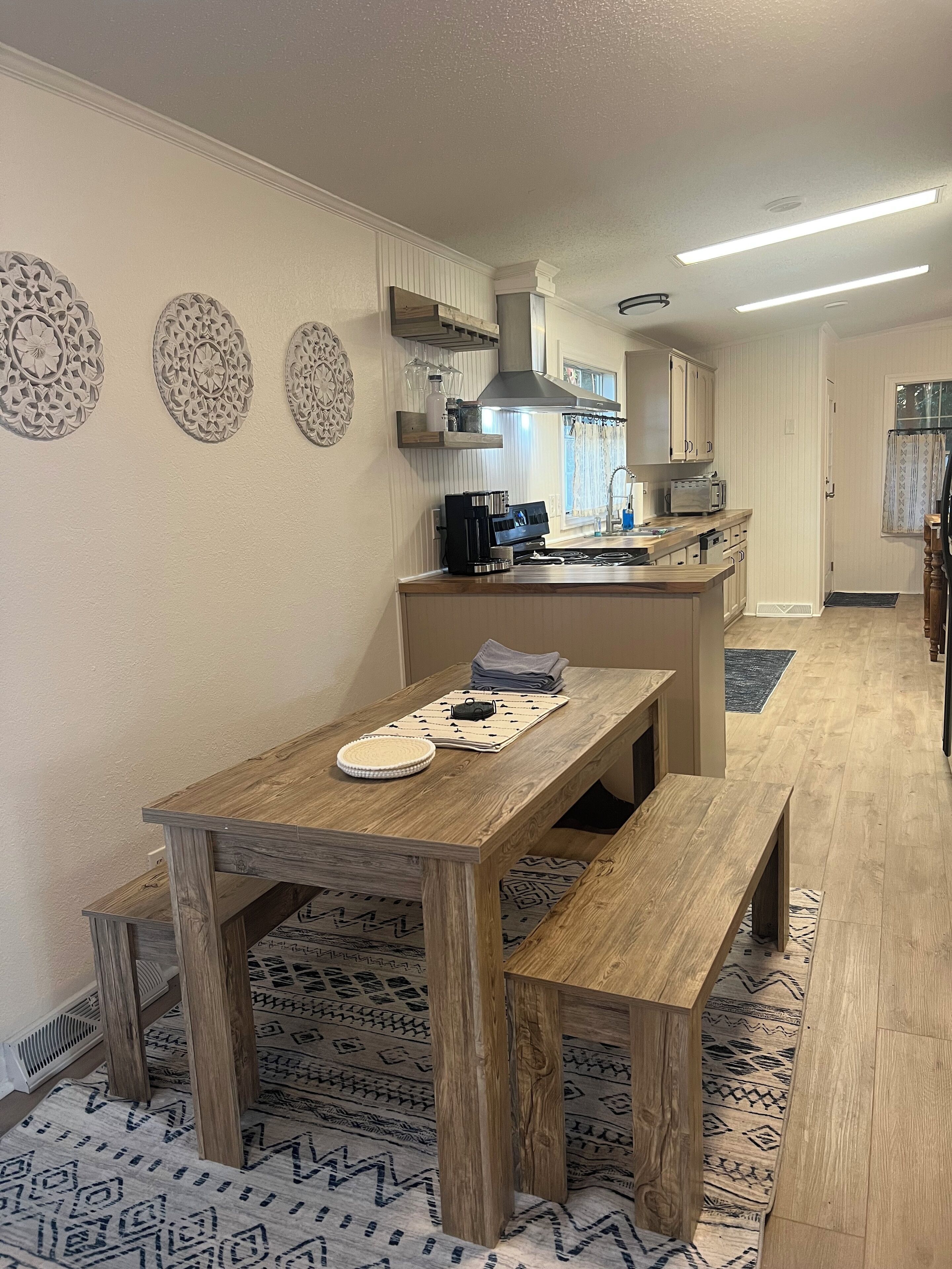 A modern kitchen with a wooden table and bench, a built-in oven, and a microwave.