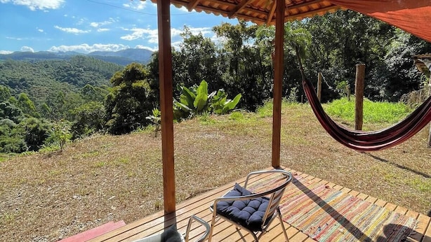 Una terraza de madera con una hamaca, una silla metálica y una mesa.