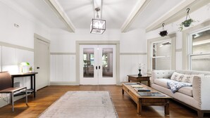 Un salón amplio con piso de madera, un sofá color beige, una mesa de centro y una planta colgante.