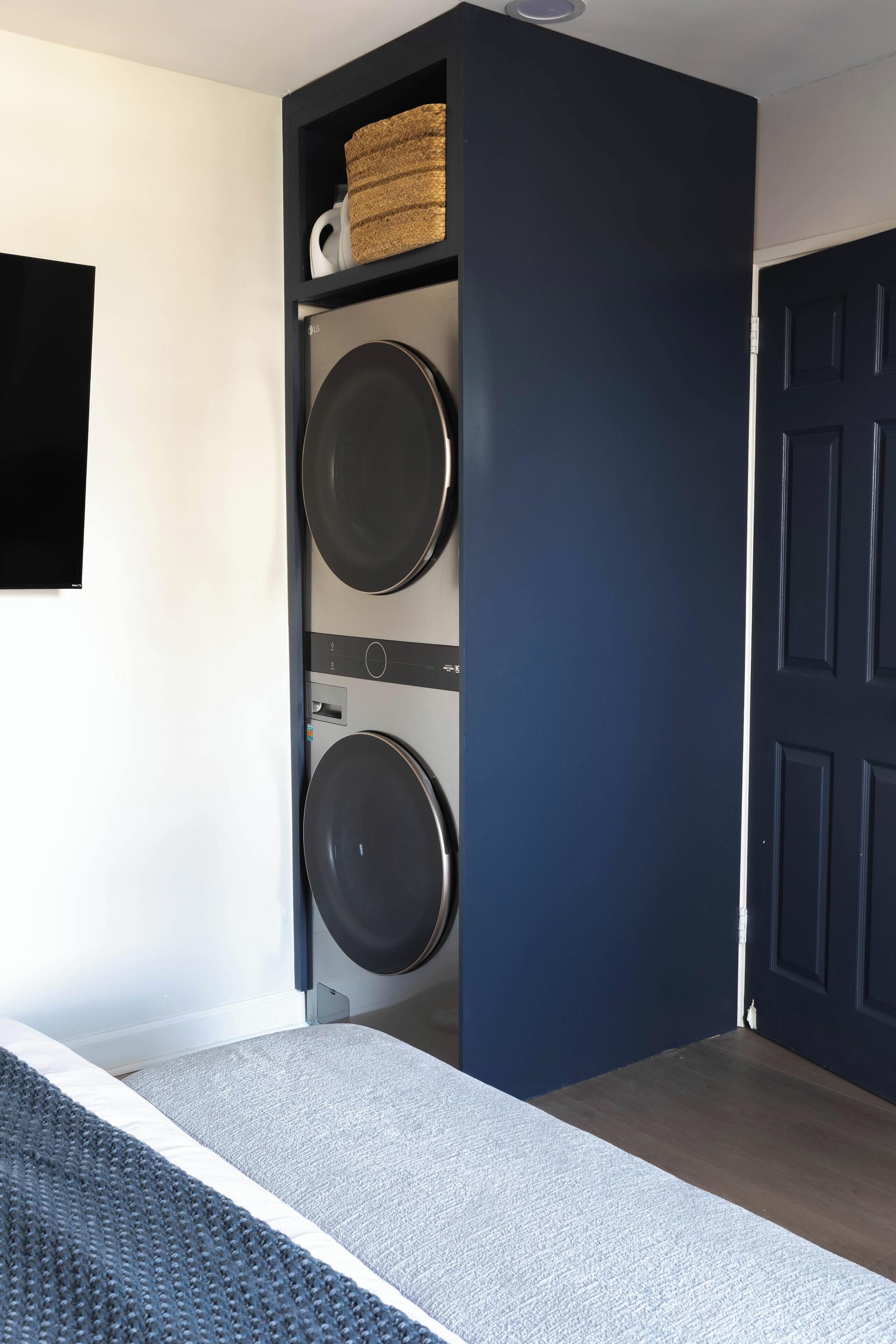 A laundry room with a dark blue door, a washing machine, and a dryer.
