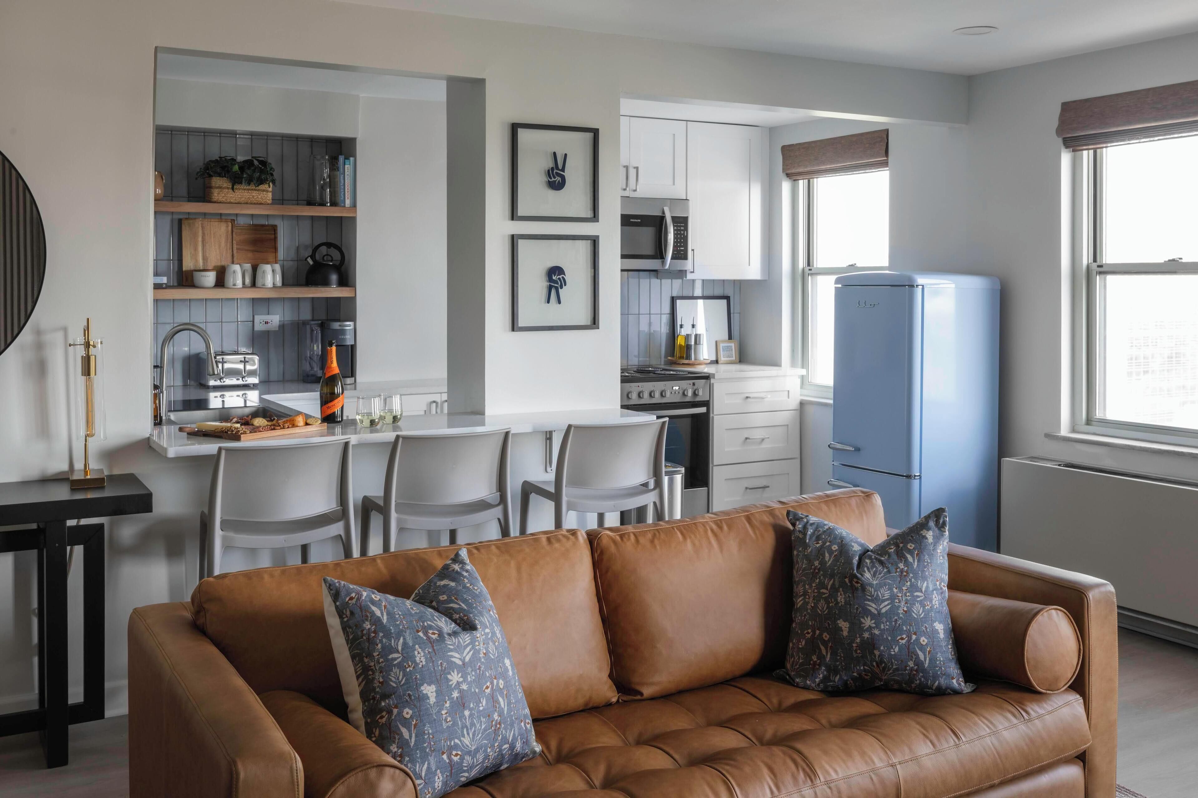 A modern kitchen with white cabinets, a built-in microwave, and a blue refrigerator.