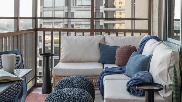 A balcony with a sofa, ottoman, and table, overlooking a cityscape. - Downtown ATL Condo Balcony (Atlanta)