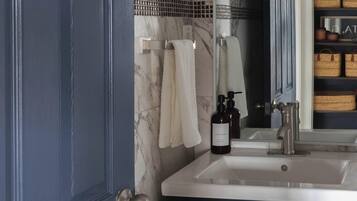 A bathroom with a dark blue door, a white sink, and a mirror above it.