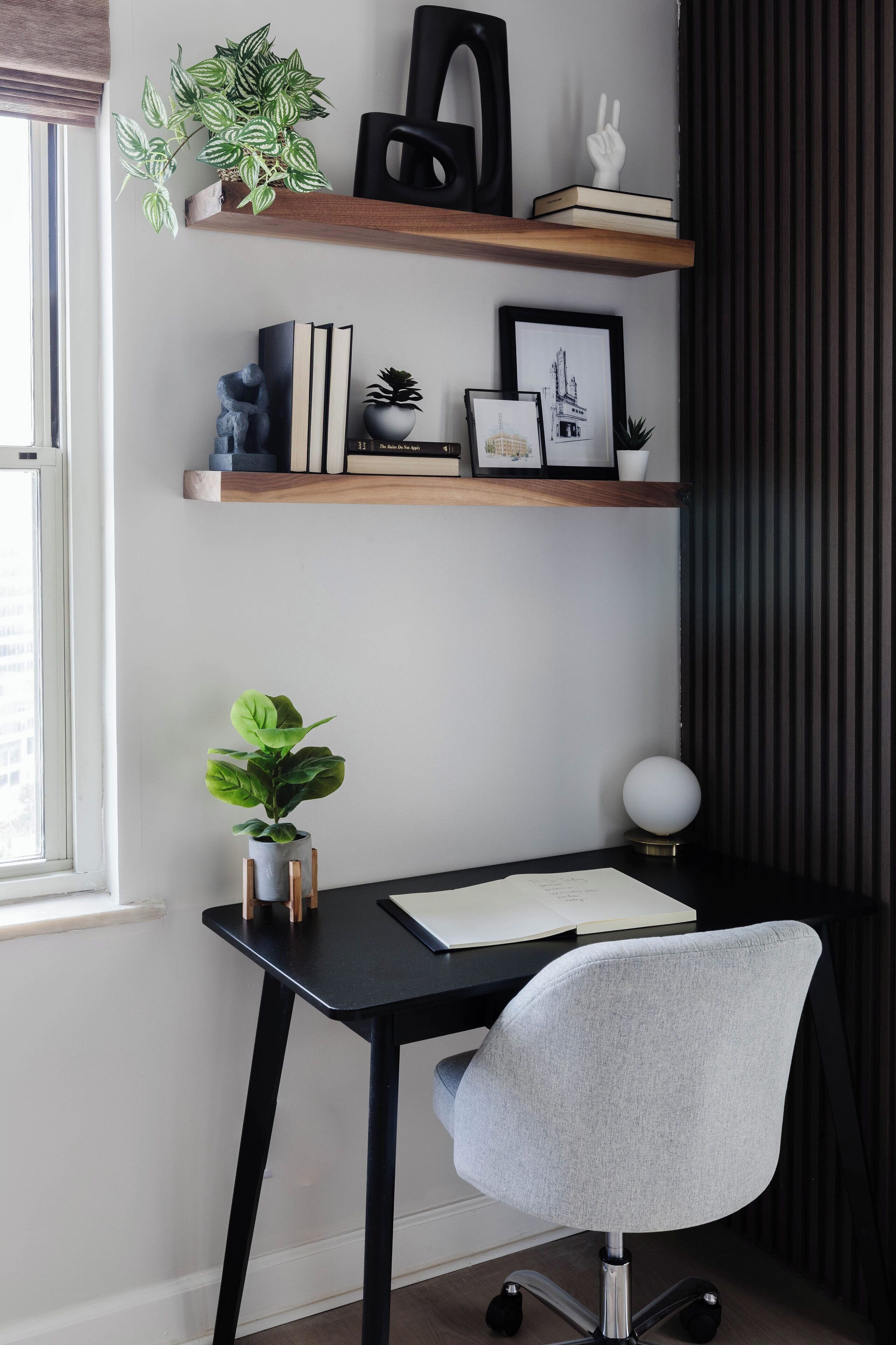 Ein Schreibtisch mit Stuhl, ein Blumentopf und ein Regal mit Büchern und Dekoration.