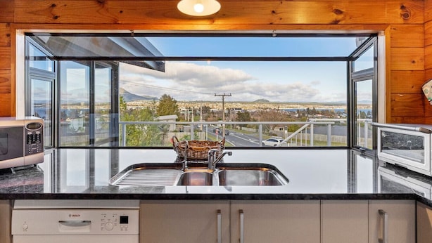 A kitchen with a large window offering a view of a cityscape and mountains.