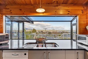 A kitchen with a large window offering a view of a cityscape and mountains.