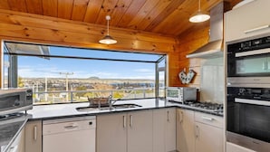 A modern kitchen with a view of a cityscape, wooden ceiling, and a Bosch microwave.