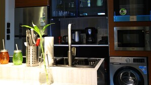 A modern kitchen with stainless steel appliances, a built-in oven, and a washing machine. - Lovely apartment with AC in vibrant Riyadh (Riyadh)