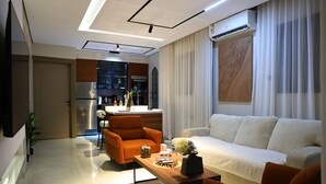 A modern living room with a sofa, armchairs, a coffee table, and a kitchen area with cabinets and appliances. - Lovely apartment with AC in vibrant Riyadh (Riyadh)