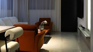 A modern living room with a sofa, armchair, and a flat-screen TV mounted on the wall. - Lovely apartment with AC in vibrant Riyadh (Riyadh)