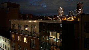 Un edificio de varios pisos con fachada de vidrio, una entrada visible en la planta baja y una calle en primer plano.
