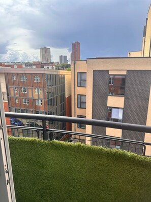 A view of a building with a balcony, featuring a metal railing and a grassy area in the foreground. - Charming Birmingham Apartment With Mini Balcony and Wifi With a Free Parking (Birmingham)