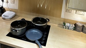 A kitchen with a stainless steel range hood, a stove with pots and a pan, and a coffee maker. - One Bedoom Flat in Birmingham City Centre With Free Underground Parking (Birmingham)