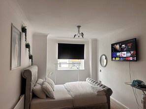 A bedroom with a bed, a TV mounted on the wall, a window, and a ceiling light. - One Bedoom Flat in Birmingham City Centre With Free Underground Parking (Birmingham)