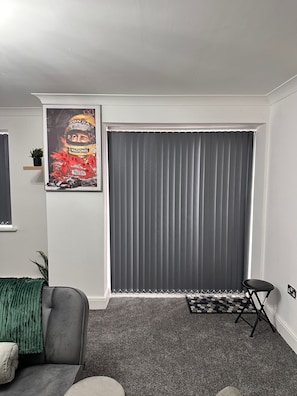 A living room with a grey sofa, a green throw, a small table, and a poster on the wall. - One Bedoom Flat in Birmingham City Centre With Free Underground Parking (Birmingham)