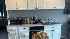 A modern kitchen with white cabinets, a marble countertop, and a vase of dried flowers.