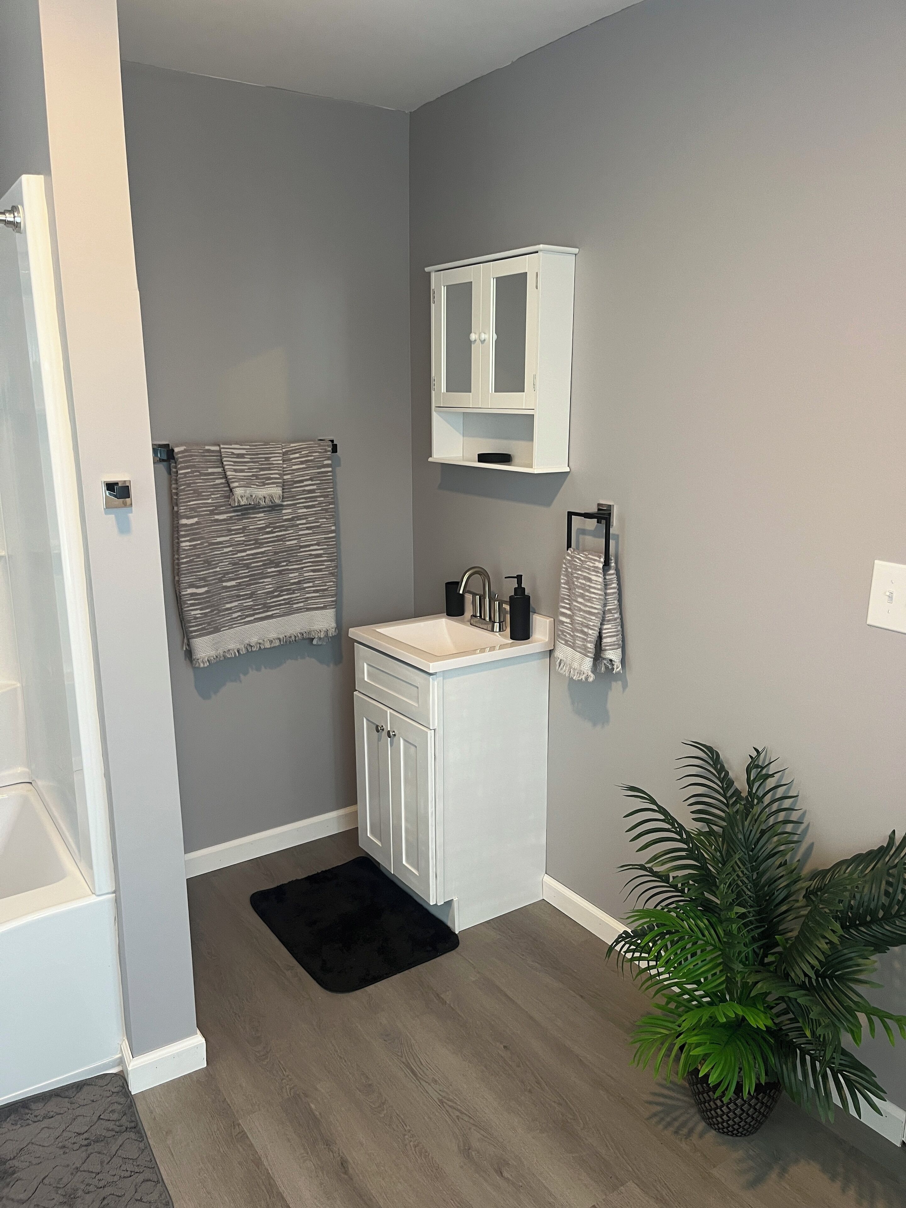 A bathroom with a white vanity, a towel rack, a sink, and a potted plant.