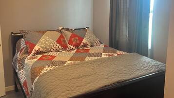 Un dormitorio con una cama, un ventilador de techo y una ventana con cortinas.