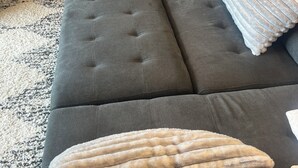 A grey sectional sofa with tufted detailing and multiple cushions.
