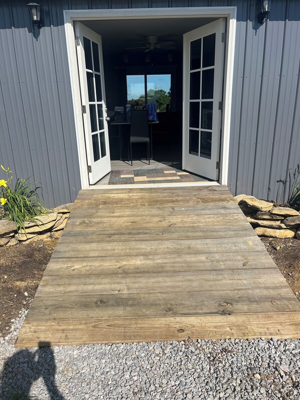 A wooden deck leading to a building with a sliding glass door.