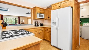 Una cocina con armarios de madera, un refrigerador blanco, un microondas, una estufa y una cafetera.