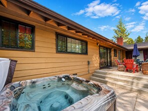 A wooden house with a hot tub in the backyard, outdoor seating, and a clear sky. - Wanderlust Lodge (Big Bear Lake)