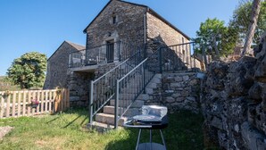 A stone building with a balcony and a staircase leading to a second floor.