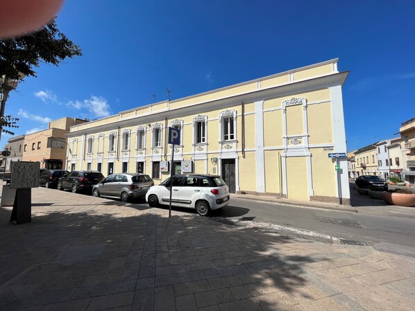 Une rue bordée de voitures garées et un bâtiment sur lequel est apposée une enseigne indiquant un espace de stationnement.