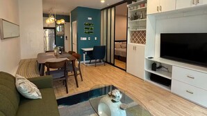 A modern living room with a sofa, a coffee table, a TV, and a ceiling fan. - Jr 1 BR w/ parking & a plunge in Design District (San Francisco)