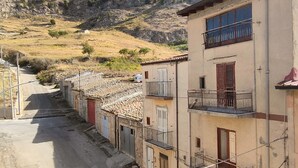 Une rue étroite bordée d’immeubles dotés de balcons, qui mène à une colline.