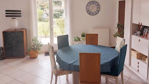 A dining area with a round table, chairs, a clock, and a radiator.